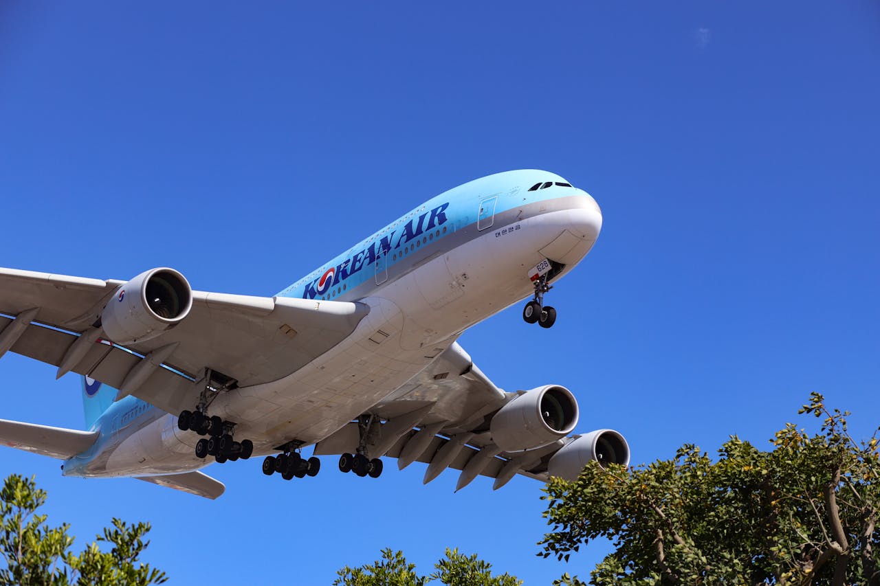 services-01 A large airliner flying low against a clear blue sky, captured in daytime.