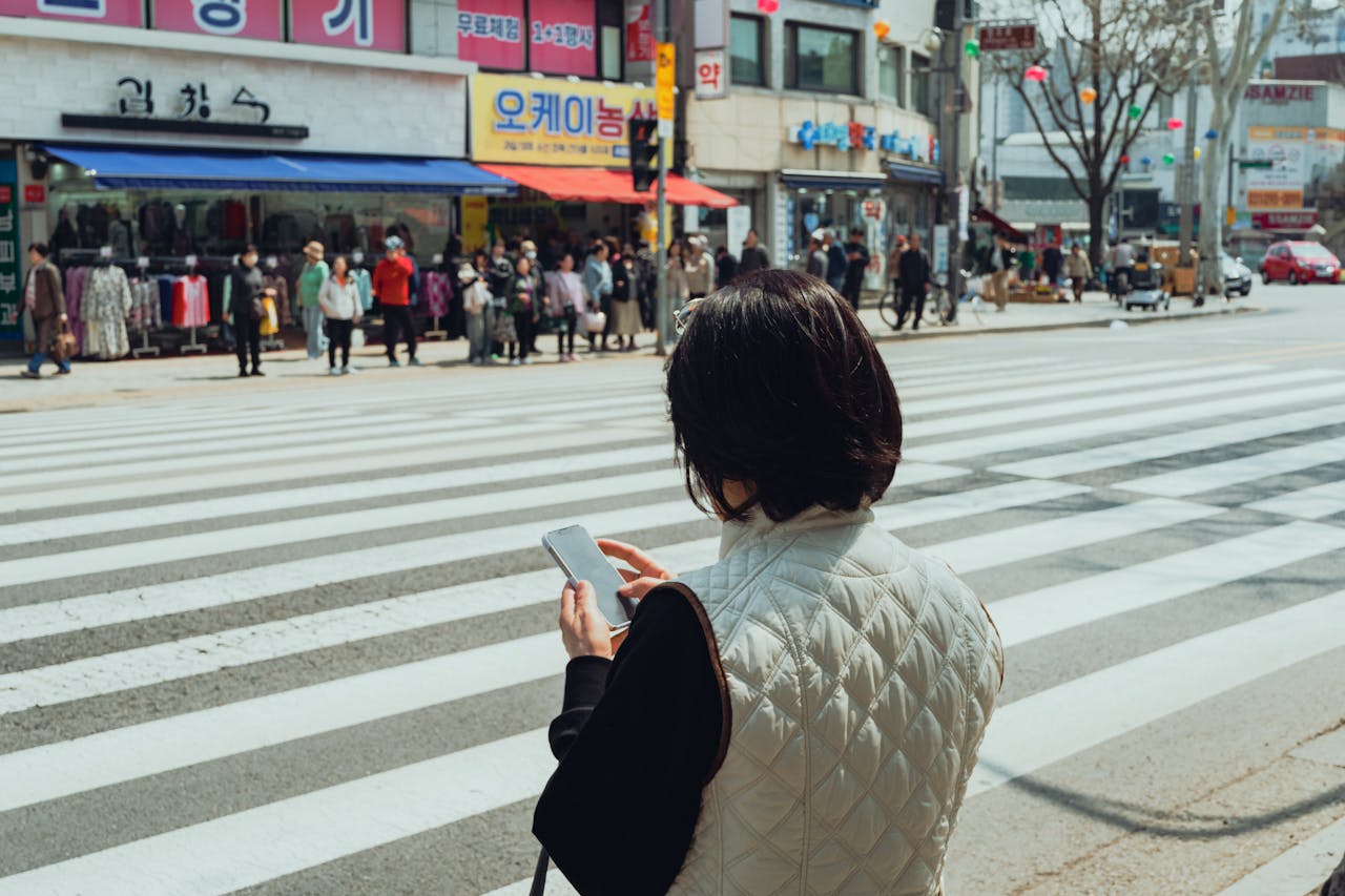 A woman checks her phone while crossing a busy street in Suwon, South Korea.