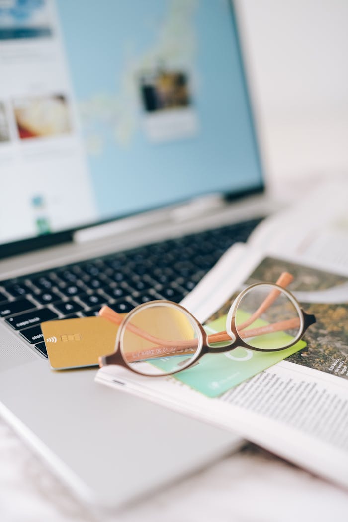 Close-up of eyeglasses and credit cards on a laptop, depicting a modern lifestyle scene.